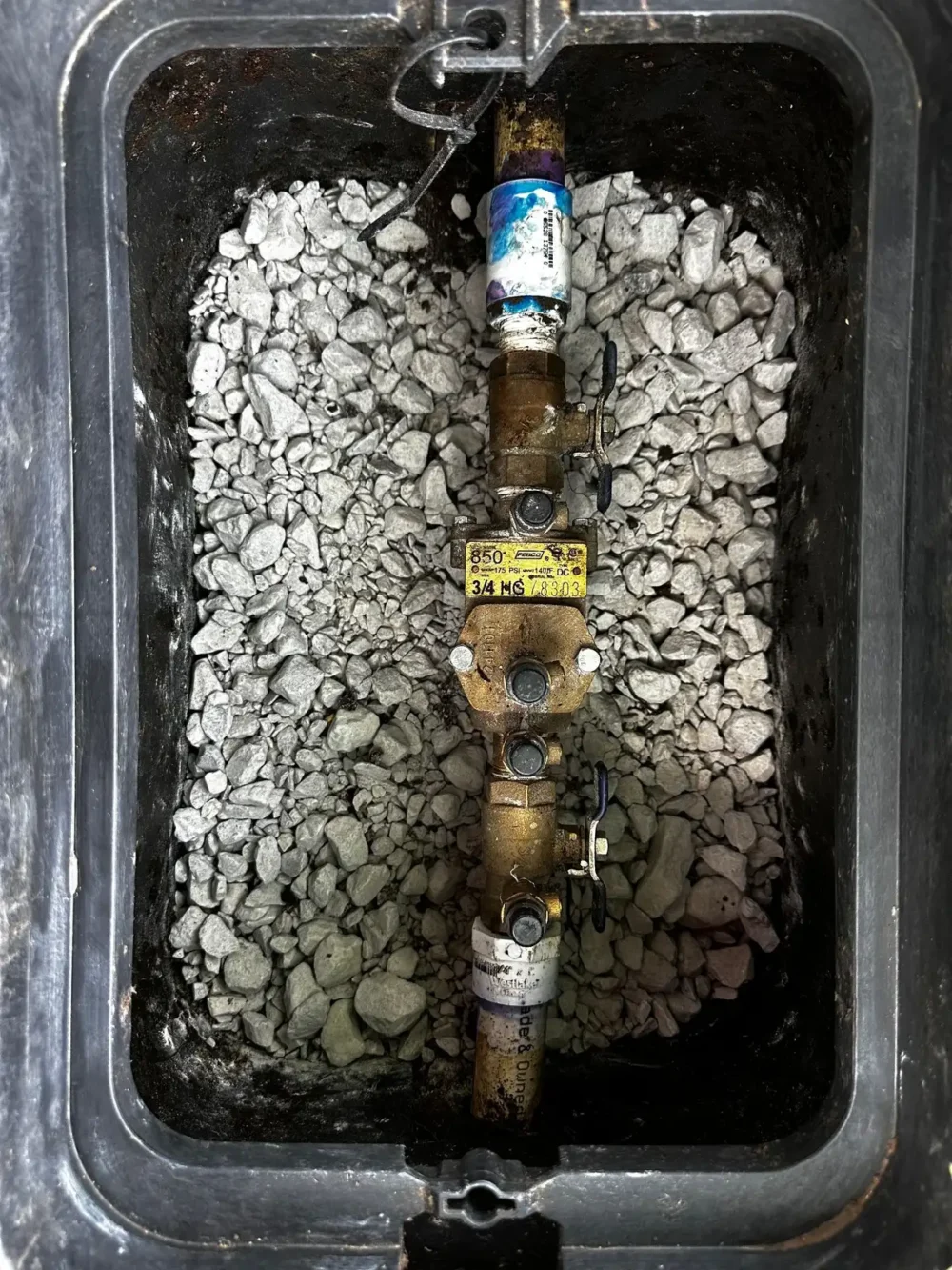 Backflow prevention device installed in a valve box on a gravel bed