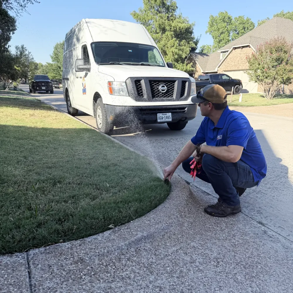 Lone Star Irrigation technician adjusting a sprinkler head at the curb, company van behind