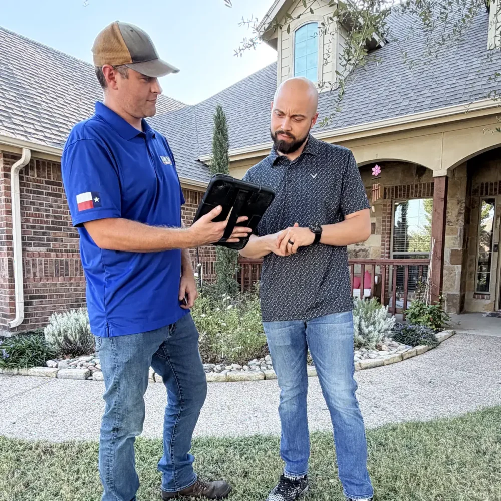 Technician walking a homeowner through a written quote on a tablet in the front yard